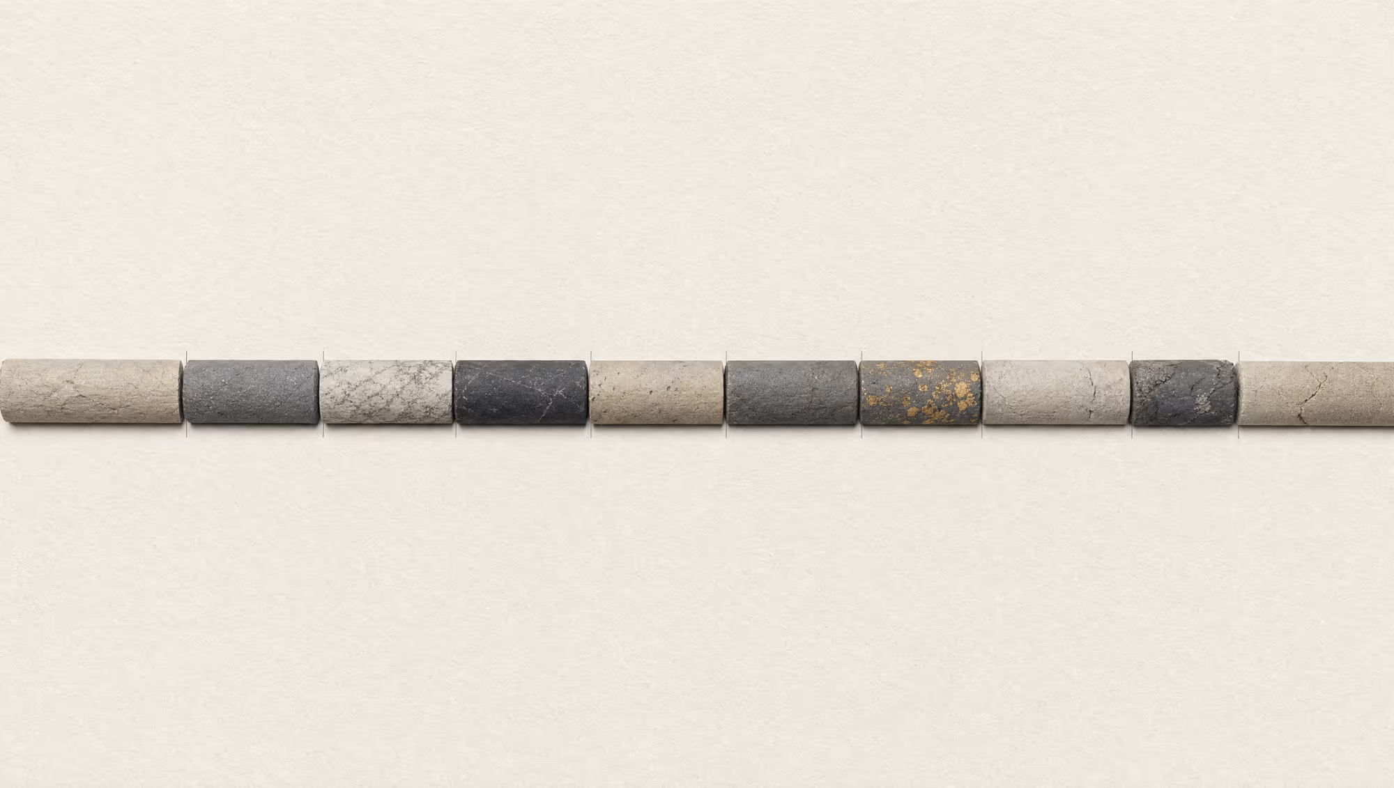 A single row of geological drill-core segments in muted earth tones, with one short interval flecked with gold.
